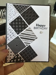 a person holding up a birthday card with black and white designs on it, which reads happy birthday