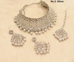 * SIlver choker necklace Set with earrings Tikka as shown in the pic. * Studded with crystals and rhinestones. * One of a Kind. *No.1- Silver *Necklace Width- 1.6 inches(included drops) * Earrings Length: 2.3 inches(included drops) *Earrings Breadth- 1.6 inches *No.2- silver *Necklace Width- 2 inches(included drops) * Earrings Length: 2.6 inches(included drops) *Earrings width- 1.4 inches White Metal Choker For Wedding, White Metal Wedding Choker, Traditional Silver Choker For Formal Occasions, Traditional Silver Formal Choker, Silver Metal Choker Jewelry Sets, Bridal Necklace With Silver Beads For Wedding, Silver Jewelry Sets With Silver Beads As Gift, Silver Choker Jewelry Sets As Gift, Silver Round Choker For Party