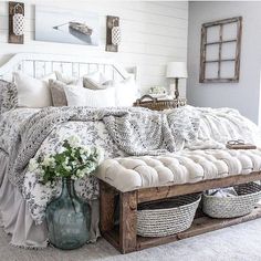 a bed with white sheets and pillows in a room next to a vase filled with flowers