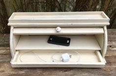 an old white wooden shelf with two charging outlets and a charger plugged into it