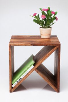 a small wooden table with a potted plant and books on the shelf next to it