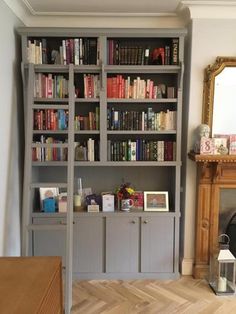 a living room filled with lots of books on top of a book shelf next to a fire place