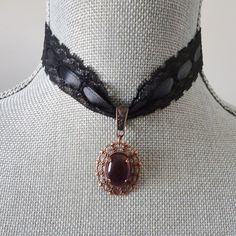 "Black lace is threaded with a black satin ribbon in this pendant choker style necklace.  The length of the choker is adjustable between 13 1/2 and 15\". The lace and ribbon portion is crimped with antique copper crimp bars and linked to a matching extension chain and lobster claw closure for adjustable sizing.  The purple glass cabochon  is set in an oval antique copper filigree metal frame and is linked to the choker with a sliding matching metal bail.  The pendant measures 7/8\" wide and the Formal Black Ribbon Choker Jewelry, Formal Adjustable Black Ribbon Choker, Adjustable Black Ribbon Choker Jewelry, Adjustable Black Ribbon Choker, Gift Black Ribbon Choker Necklace, Vintage Black Jewelry With Adjustable Cord, Adjustable Black Oval Necklace, Black Ribbon Choker Necklace, Antique Choker