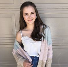 a young woman standing in front of a garage door wearing jeans and a white top