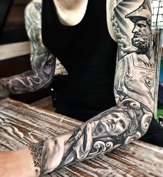 a man sitting at a table with his arm covered in tattoos