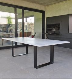 a white table sitting on top of a tiled floor next to a glass wall with sliding doors