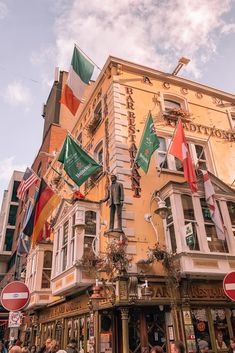 a tall building with many flags hanging from it's sides on a city street