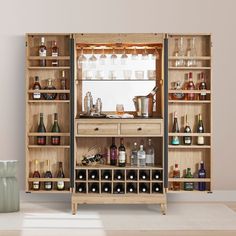 a wooden cabinet filled with lots of bottles and glasses next to a vase on the floor