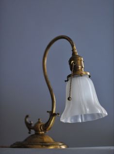 an antique brass desk lamp with a white glass shade