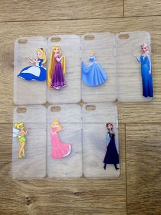 four cell phones with princesses on them sitting on top of a wooden table next to each other