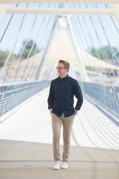 a man standing on a bridge with his hands in his pockets