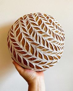 a person holding up a round object made out of clay and paper mache with leaves on it