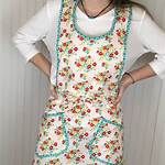 a woman standing with her hands on her hips wearing an apron and smiling at the camera