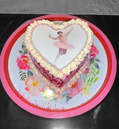 a cake shaped like a heart with a ballerina figure on the top and flowers around it