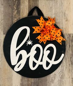 a black and white sign that says boo with orange polka dot bows on it's head