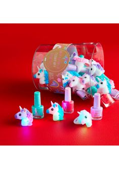 an open plastic container filled with lots of little pony toys on top of a red surface