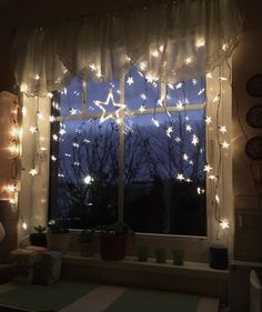 the window is decorated with fairy lights and stars on it's curtained windowsill