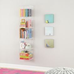 a book shelf with several books on it in the corner next to a pink rug