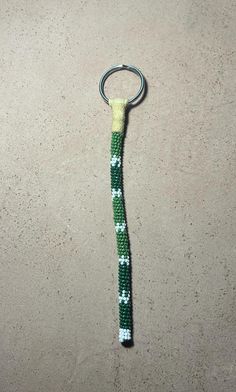 a green and white knitted keychain hanging from a hook on a wall