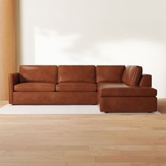 a brown leather couch sitting on top of a hard wood floor next to a white rug