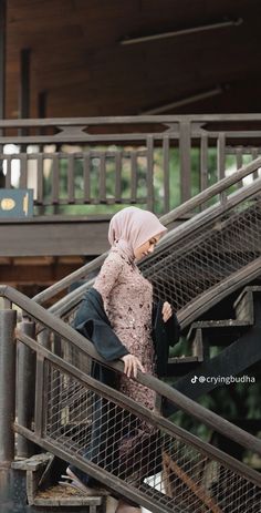 a woman in hijab walking down some stairs with her hand on the railing