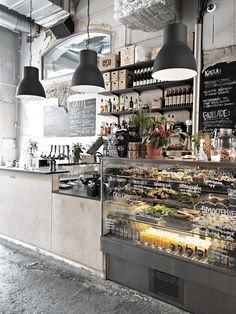 a bakery with lots of food on the counter and hanging lights over it's windows