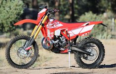 a red dirt bike parked on top of a dirt road