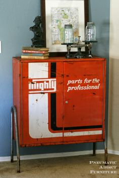 a red cabinet with an advertisement on the front and bottom, sitting next to a blue wall