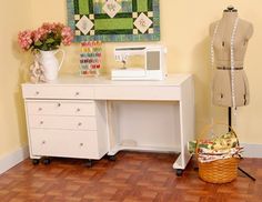 a sewing machine sitting on top of a white desk next to a vase with flowers