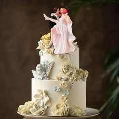 a wedding cake decorated with flowers and a bride and groom figurine on top