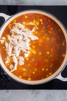 a pot filled with chicken and corn soup on top of a black stove burner