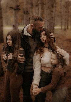 a man and two women are standing in the woods with their arms around each other