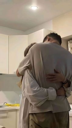 two people hugging each other in the kitchen