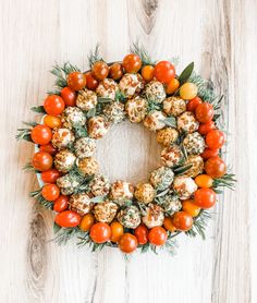 a wreath made out of tomatoes and other vegetables on a wooden surface with the words, christmas