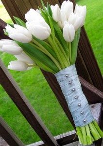 a vase filled with white flowers sitting on top of a wooden bench