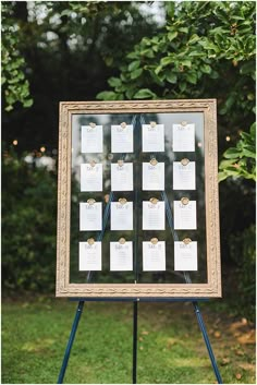 a wedding seating chart on a easel in front of some green grass and trees