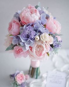 a bouquet of flowers sitting on top of a white table next to a card holder