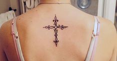 a cross tattoo on the back of a woman's upper arm and lower back