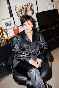 a woman sitting in a chair wearing a black suit