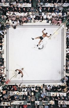 an overhead view of a wrestling match with the referee in mid air, surrounded by spectators