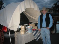 a man standing in front of a tent next to a table with food on it