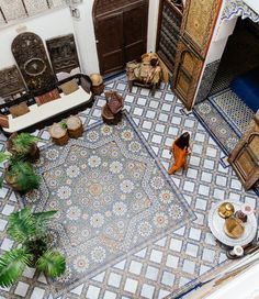 an aerial view of a living room with blue and white tiles on the floor, potted plants, and two couches