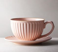 a pink coffee cup and saucer on a white table