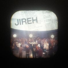 a group of people standing in front of a large screen with the word jireh on it