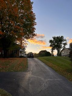 an empty street with houses and trees in the background at sunset or sunrise, on a fall day