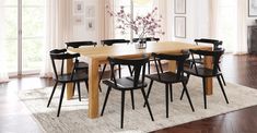 a dining room table with black chairs and a white rug on the floor in front of it