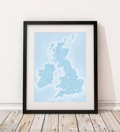 a framed map of the united kingdom in blue on a white wall next to a wooden floor