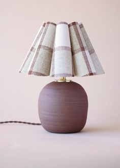 a brown table lamp sitting on top of a white floor next to a pink wall