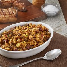 a white bowl filled with stuffing next to some meat