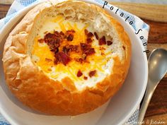 a white plate topped with a bread bowl filled with cheese and bacon